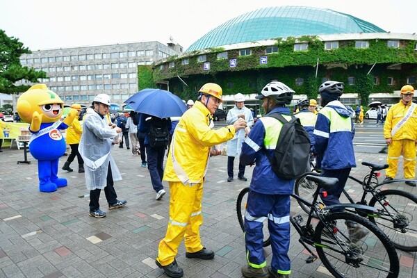 HD현대중공업 노진율 대표이사(사진 가운데 노란색 우의)를 비롯한 HD현대중공업 임원들과 고용노동부 울산지청, 한국산업안전보건공단 울산지역본부 관계자들이 출근길 직원들에게 안내문과 음료를 나눠주며 안전작업을 당부하고 있다. [제공=HD현대중공업]