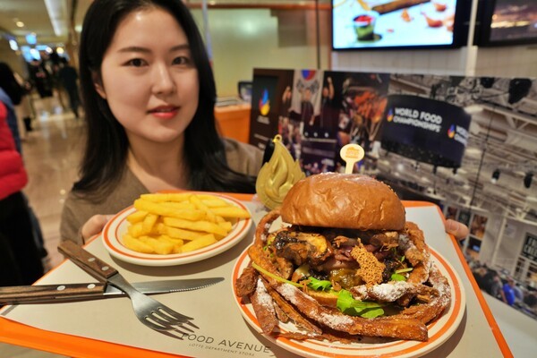 본점 지하 1층 '멜팅소울' 매장에서 '리틀 빅 포레스트 잠봉버거'를 들고 있는 모델. [제공=롯데백화점]