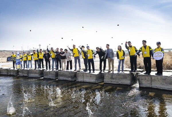 오비맥주 이천공장 임직원들과 이천시청 관계자들이 지난 13일 경기 이천시 복하천에서 ‘EM 흙공 던지기’를 하며 하천 정화 활동을 펼치고 있다. [출처=오비맥주]