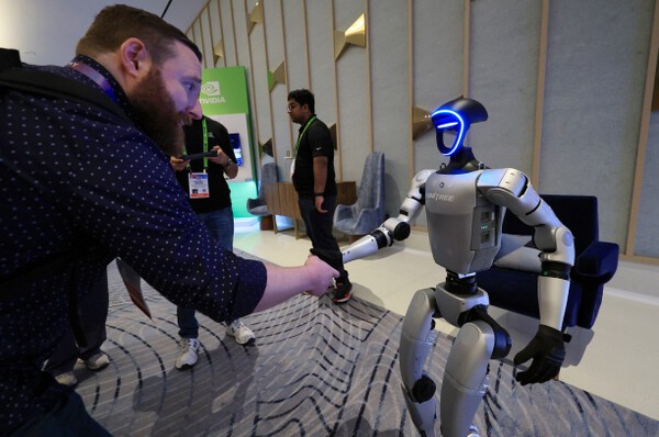CES 2025에서 휴머노이드 로봇 유니트리 G1이 관람객과 악수하고 있다. [출처=연합뉴스]