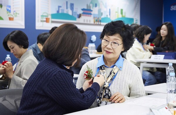 SBI저축은행이 진행한 가족 초청 행사 ‘부모님 오신데이(Day)’에서 직원들이 부모님께 카네이션을 달아드리고 있다. [출처=SBI저축은행]