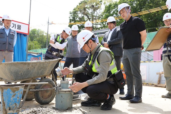 롯데건설 직원이 서초 헌인마을 현장에서 ‘차세대 혼화제’가 적용된 콘크리트를 테스트하고 있다.[출처=롯데건설]