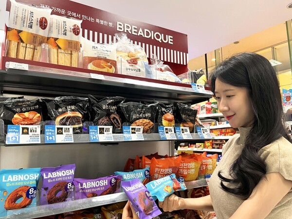 GS25에서 모델이 랩노쉬 프로틴 휘낭시에 플레인, 랩노쉬 프로틴 도넛 초코를 바라보고 있다. [출처=GS25]