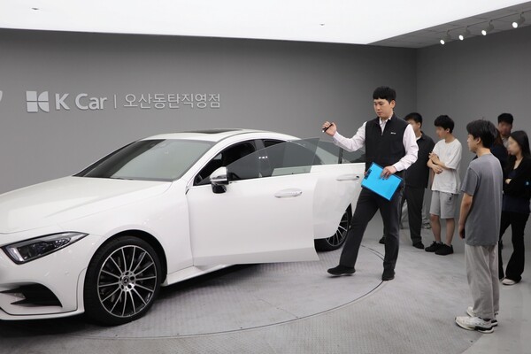 케이카가 13일 서울 소재 대안학교 재학생 약 30명을 대상으로 직업 체험 프로그램을 3년 연속 진행했다. 성강훈 케이카 오산동탄지점 판매실장이 학생들에게 차량 진단 과정을 설명하고 있다. [출처=케이카]