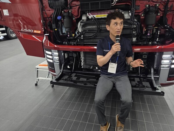 연구원이 프론트 범퍼에 앉아 엑시언트 특징을 설명하고 있다 [출처=박성호 기자]