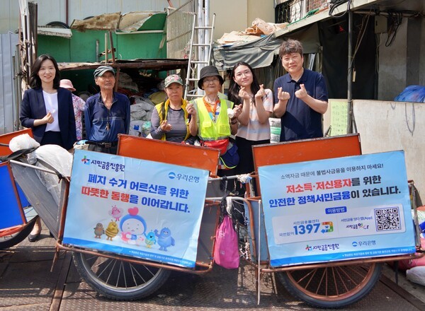 지난 19일 우리은행, 서민금융진흥원, 협동조합 끌림이 함께 폐지수거 어르신들에게 경량 리어카와 안전용품을 제공했다. 우리은행 하현신 상생금융부장(좌측)과 서민금융진흥원 신승주 홍보협력실장(우측)이 전달식 이후 어르신들과 함께 기념사진을 촬영하고 있다. [출처=우리은행]