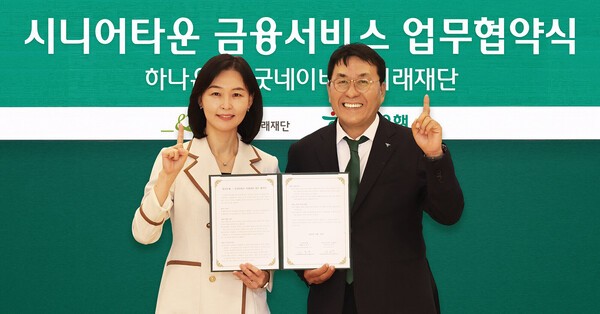 협약식에 참석한 김진우 하나은행 중앙영업그룹 부행장(사진 오른쪽)이 양진옥 굿네이버스 미래재단 대표와 함께 업무협약서를 들고 기념 촬영을 하고 있다. [출처=하나은행]