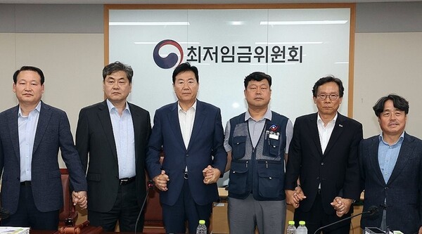 이인재 최저임금위원장(왼쪽 두 번째)이 10일 정부세종청사에서 열린 제12차 전원회의에서 내년 최저임금을 시간당 1만320원으로 17년만에 합의로 결정한 뒤 공익위원-사용자위원-근로자위원과 손을 잡고 있다.[출처=연합]