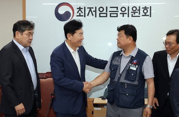 최저임금위원회 사용자위원 운영위원인 류기정 한국경영자총협회 전무(왼쪽)와 근로자위원 운영위원인 류기섭 한국노총 사무총장이 10일 정부세종청사에서 열린 제12차 전원회의에서 내년 최저임금을 시간당 1만320원으로 17년 만에 합의로 결정한 뒤 악수하고 있다. 왼쪽은 이인재 위원장, 오른쪽은 이명로 중소기업중앙회 인력정책본부장. [출처=연합]