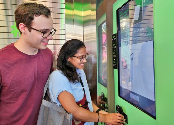 미국인 탄비(Tanvi, 오른쪽)씨와 러셀(Russell, 왼쪽)씨가 올리브영 명동 타운에 마련된 벤딩머신으로 글로벌몰에 가입하는 모습. [출처=CJ올리브영]