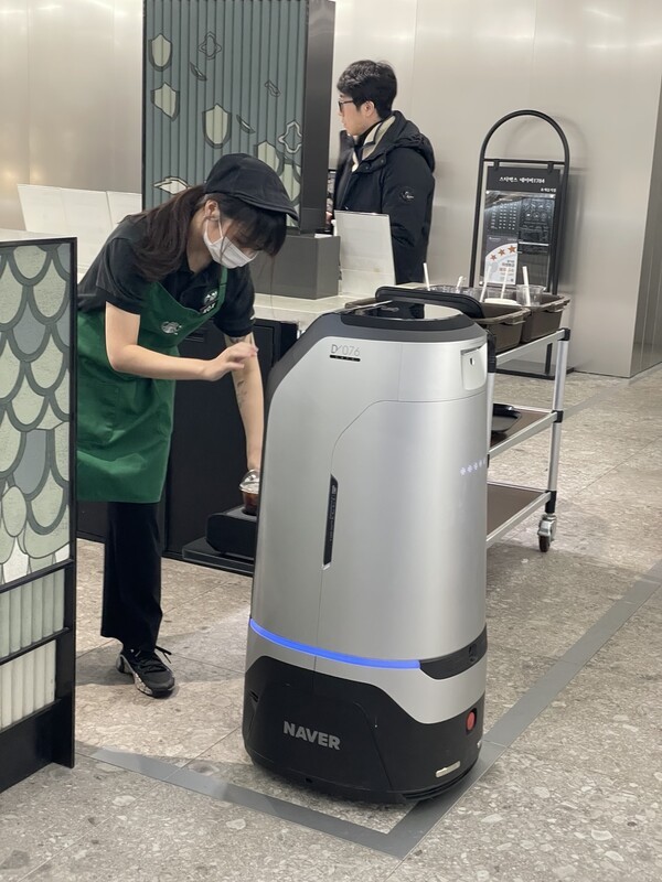 네이버의 서빙·배달 로봇 '루키'에게 커피점 직원이 커피를 놓고 있다. 루키는 커피를 받고 수령처로 이동한다. [출처=이경은 기자 ]
