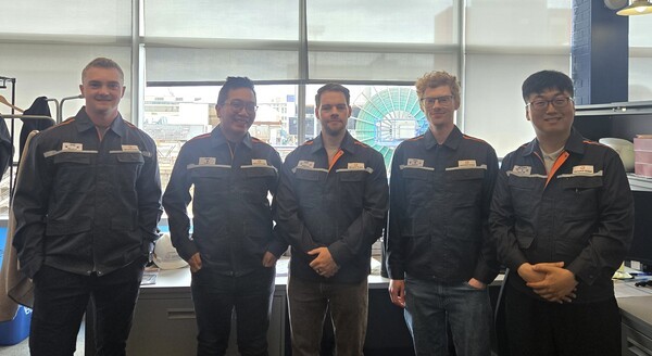 이상욱 책임(오른쪽)과 현지 직원들이 한화오션 작업복을 입고 기념 촬영을 하고 있다. [출처=한화오션]