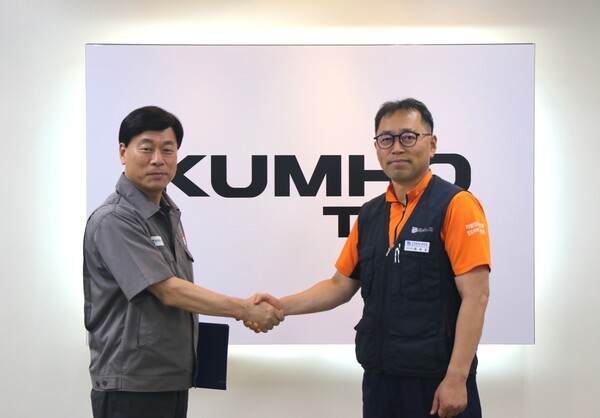 김명선 금호타이어 생산기술총괄 부사장(사진 왼쪽)과 황용필 금호타이어지회 대표 지회장이 노사 특별합의문을 들고 사진을 찍고 있다. [출처=금호타이어]