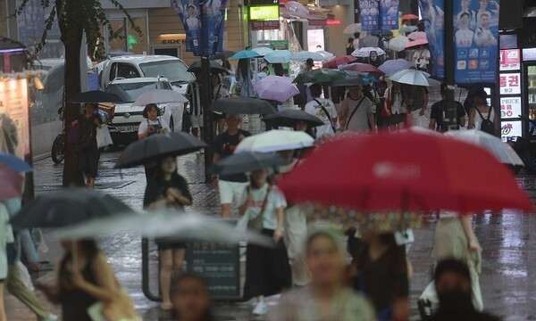 외국인 관광객들이 지난 6일 비가 내리는 서울 명동거리를 우산을 쓴 채 지나가고 있다. [출처=연합뉴스]
