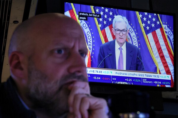 10월 29일 미국 뉴욕시 뉴욕증권거래소(NYSE)에서 미국 연방준비제도이사회(Fed) 의장 제롬 파월이 금리 인하를 발표한 후 기자회견을 하는 모습이 화면에 나오는 가운데, 한 트레이더가 작업하고 있다. [출처=연합뉴스]